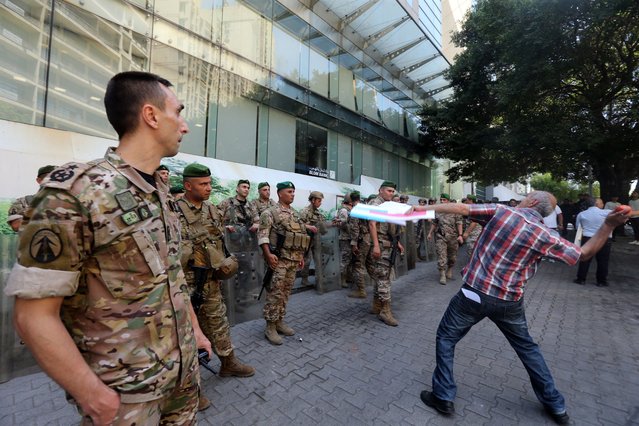 A protester throws tomatoes at the BLOM Bank building during a protest organized by the Union of Lebanese Expatriates Depositors and Depositors' Outcry, a group campaigning for the rights of depositors, in Beirut, Lebanon, 04 July 2025. Bank customers gathered outside Lebanon's Central Bank to protest the continued restrictive measures on bank deposits, which have been in place since 2019. They also object to a decision by the central bank to return people's savings over an undisclosed number of years. (Photo by Wael Hamzeh/EPA)