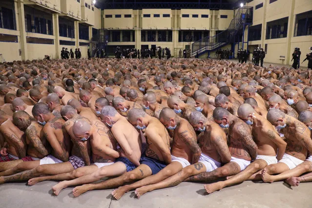 In this photo released by El Salvador Presidency Press Office police wearing masks as precautions against the new coronavirus guard inmates, also wearing masks, during a security operation after President Nayib Bukele decreed maximum emergency in prisons housing gang members at the Izalco prison in San Salvador, El Salvador, Saturday, April 25, 2020. Bukele ordered the emergency the day after more than twenty people were killed throughout country that authorities said were ordered from prisons. (Photo by El Salvador President Press Office via AP Photo)