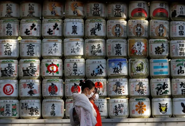 Kimono-clad women wearing protective face masks walk in front of Japanese Sake barrel decorations for the year-end and New-Year at Meiji Shrine, amid the coronavirus disease (COVID-19) outbreak, in Tokyo, Japan, December 31, 2020. (Photo by Issei Kato/Reuters)