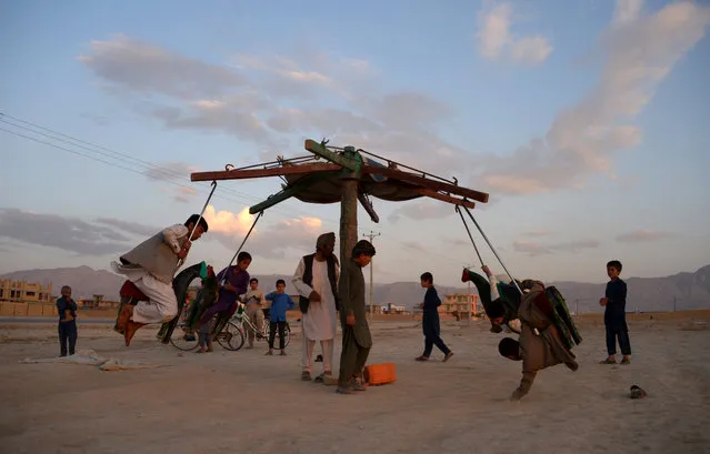 In this photo taken on May 22, 2018 Afghan youths play on a swing at sunset on the outskirts of Mazar-i-Sharif, Afghanistan. (Photo by Farshad Usyan/AFP Photo)