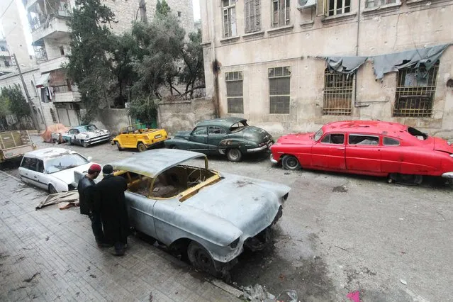Mohamed Badr al-Din (R) stands next to his vintage cars along a street where he keeps them, in the al-Shaar neighborhood of Aleppo January 31, 2015. (Photo by Abdalrhman Ismail/Reuters)