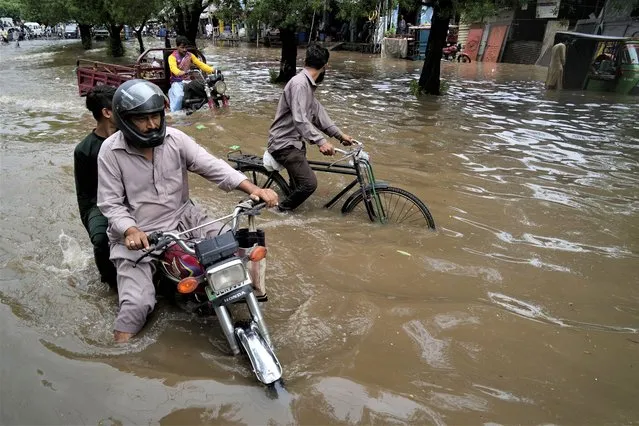 Motorcyclists drive through a flooded road caused by heavy rainfall, in Lahore, Pakistan, Monday, June 26, 2023. (Photo by K.M. Chaudary/AP Photo)