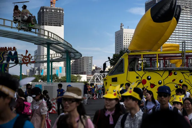 People walk in front of an amphibious bus featuring an advertisement of Pikachu, a character from Pokemon series game titles, during the Pikachu Outbreak event hosted by The Pokemon Co. on August 10, 2018 in Yokohama, Kanagawa, Japan. (Photo by Tomohiro Ohsumi/Getty Images)