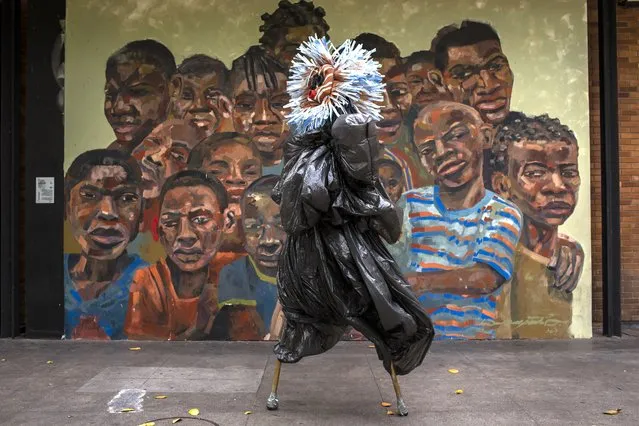 A performing artist balances on stilts dressed in a costume representing ancestral spirits during a video recording of “Giant Dreamers” outside the MAM or Museum of Modern Art (MAM) during the COVID-19 pandemic in Rio de Janeiro, Brazil, Tuesday, March 9, 2021. The show is funded by the government and features artists recreating the magic of Carnival. (Photo by Bruna Prado/AP Photo)