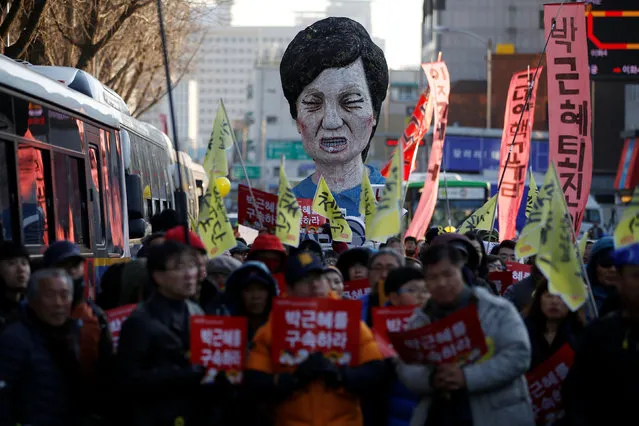 An effigy of South Korean President Park Geun-hye is seen behind people marching towards the Presidential Blue House during a protest calling for South Korean President Park Geun-hye to step down in central Seoul, South Korea, December 10, 2016. The signs read, “Arrest Park Geun-hye”. (Photo by Kim Hong-Ji/Reuters)