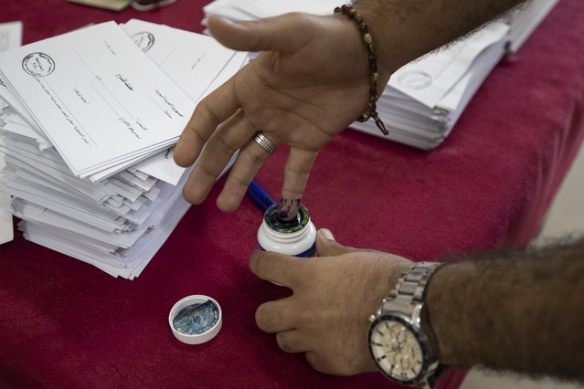 A Syrian man inks his finger after hw votes at a polling station during the Presidential elections in the Syrian capital Damascus, Syria, Wednesday, May 26, 2021. (Photo by Hassan Ammar/AP Photo)