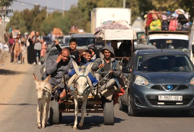Riding a donkey drawn cart as family along with hundreds of other Palestinian carrying their belongings flee following the Israeli army's warning to leave their homes and move south before an expected ground offensive, in Gaza City on October 13, 2023. (Photo by Mahmud Hams/AFP Photo)