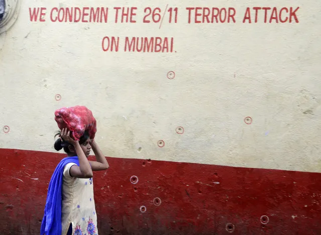 A girl walks past a wall of the Chabad House, with bullet marks on the eve of the tenth anniversary of the Mumbai terror attacks in Mumbai, India, Sunday, Nov 25, 2018. On November 26, 2008, India's financial capital Mumbai was turned into a war zone by a group of Pakistani gunmen who launched coordinated attacks in the heart of the city. They targeted two luxury hotels, a Jewish center, a tourist restaurant and a crowded train station. Three days of carnage killed 166 people, including foreign tourists, and wounded hundreds more. (Photo by Rajanish Kakade/AP Photo)