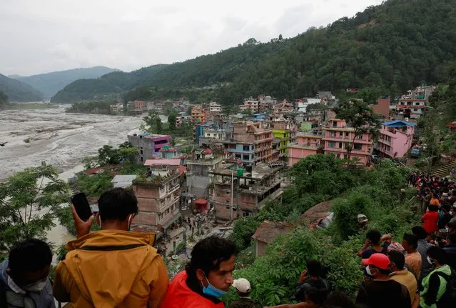 People gather on higher ground as flood water from the swollen Melamchi river enters the village in Sindhupalchok, Nepal, June 16, 2021. (Photo by Navesh Chitrakar/Reuters)