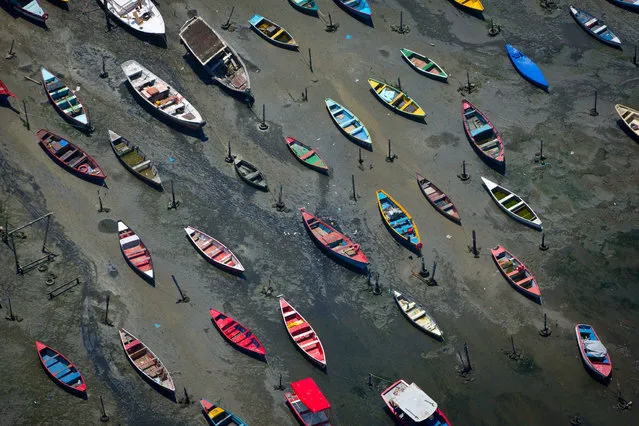 Small boats sit on the shore of Guanabara Bay in the suburb of Sao Goncalo, across the bay from Rio de Janeiro, Brazil, Tuesday, November 19, 2013. The bay was home to a thriving artisanal fishing industry and popular palm-lined beaches as recently as the late-1970s, but has become a watery dump for waste from shipyards and two commercial ports. Rio de Janeiro will host the 2016 Olympic Games. (Photo by Felipe Dana/AP Photo)