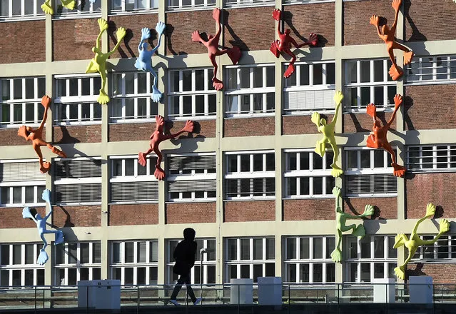 Colorful sculptures seem to climb up a building at the harbour city in Duesseldorf, Germany, Wednesday, January 4, 2017. (Photo by Martin Meissner/AP Photo)