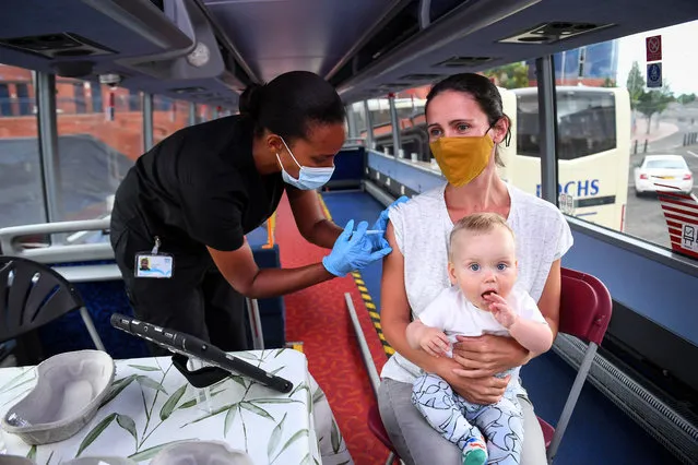 Hazel Hiram of the Scottish Ambulance Service, gives Gillian Fergusson, 40, an injection of a Covid-19 vaccine as Fergusson holds her 10-month-old son Ruairidh McElwee on the Scottish Ambulance Service vaccine bus in Glasgow on July 28, 2021. (Photo by Andy Buchanan/AFP Photo)