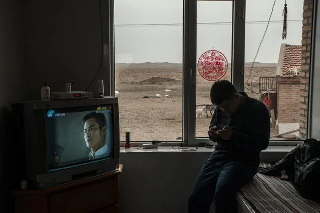 A herder checking his phone at home near an army training camp. The eviction of herders from their grassland for the extension the training base has led to protests. (Photo by Gilles Sabrie/The Washington Post)