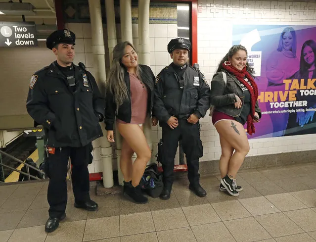 Two women pose for a photograph with a pair of New York City police officers at the Union Square station at the culmination of the 18th annual No Pants Subway Ride, January 13, 2019, in New York. (Photo by Kathy Willens/AP Photo)