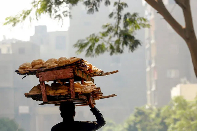 A bakery worker carries fresh bread in Cairo, Egypt on August 1, 2021. (Photo by Amr Abdallah Dalsh/Reuters)