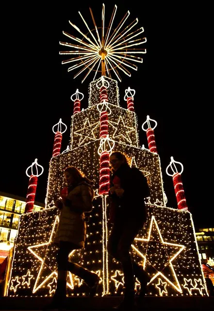 Two women walk in front of a Christmas illumination at a Christmas market in Berlin. (Photo by Markus Schreiber/Associated Press)