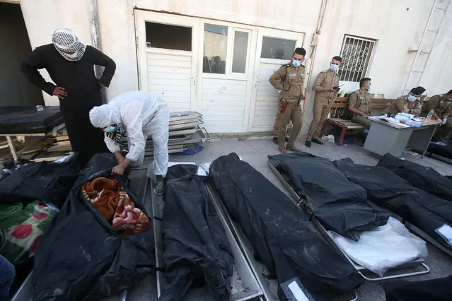 People stand near body bags containing the remains of victims after a fire broke out at al-Hussain coronavirus hospital in Nassiriya, Iraq, July 13, 2021. (Photo by Essam al-Sudani/Reuters)