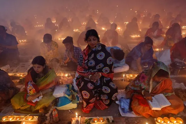 Hindu devotees sit together on the floor of a temple with oil lamps, praying to Lokenath Brahmachari, a Hindu saint, as they observe Rakher Upabash, in Narayanganj, Bangladesh on November 7, 2023. (Photo by Mohammad Ponir Hossain/Reuters)
