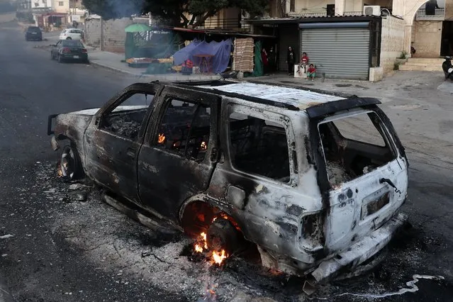 A family looks at a burning car after heavy clashes in the coastal town of Khaldeh, south of Beirut, Lebanon, Sunday, August 1, 2021. (Photo by Bilal Hussein/AP Photo)