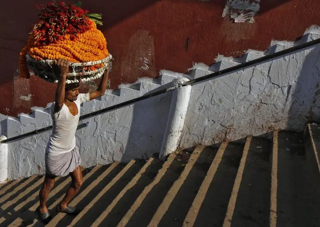 A man carries a basket of flowers as he climbs the stairs on the banks of the river Ganges towards a flower market in Kolkata, India, February 22, 2016. (Photo by Rupak De Chowdhuri/Reuters)