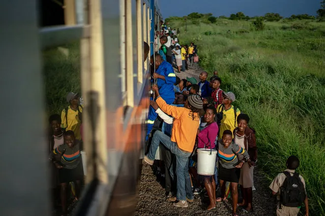 Commuters clamber aboard a train heading for the city on January 29, 2019, in Bulawayo, Zimbabwe. Zimbabwe's only commuter train is cheap and reliable -- two qualities that its passengers cherish in a downwards-spiralling economy. (Photo by Zinyange Auntony/AFP Photo)