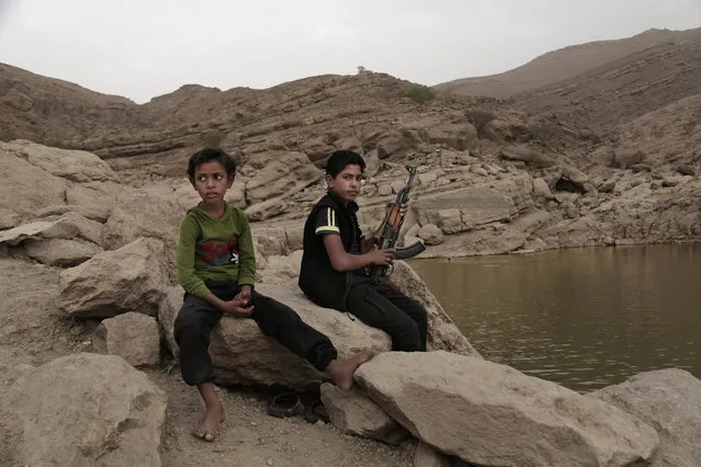 In this July 30, 2018, photo, a 17 year-old boy holds his weapon in High dam in Marib, Yemen. Experts say child soldiers are “the firewood” in the inferno of Yemen’s civil war, trained to fight, kill and die on the front lines. Though both sides in the war recruit children, the Houthi rebels rely on them the most. One Houthi military official said 18,00 children had been recruited over the past four years. (Photo by Nariman El-Mofty/AP Photo)
