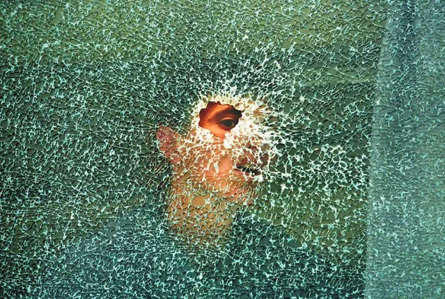 An ethnic Albanian villager looks through a bullet hole in a bus window in the village of Lapusnik 20 km south-west of Kosovo's capital Pristina, May 11, 1998. The bus was destroyed during fierce fighting between Serbian forces and ethnic Albanian separatists. (Photo by Yannis Behrakis/Reuters)