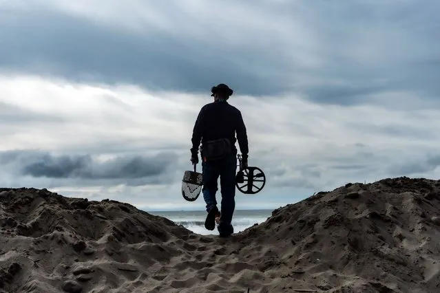 Metal detectorist Josh Snider walks over a sand mound to search for metals on the edge of the beach ahead of storms, Wednesday, January 31, 2024, in Ventura, Calif. The first of two back-to-back atmospheric rivers slowly pushed into California on Wednesday, triggering statewide storm preparations and calls for people to get ready for potential flooding, heavy snow and damaging winds. (Photo by Damian Dovarganes/AP Photo)