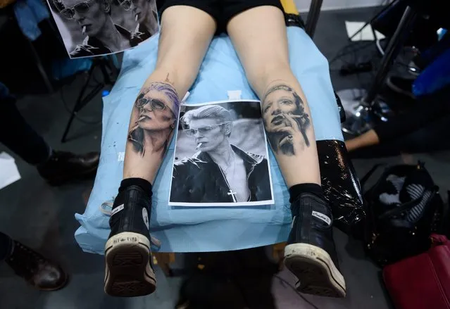 A woman displays her tattoos depicting late British musician David Bowie (L) and  late German actress and singer Marlene Dietrich (R) at the Tattoo Convention in Poznan, Poland, 20 March 2016. About 300 artists participated in the event. (Photo by Jakub Kaczmarczyk/EPA)