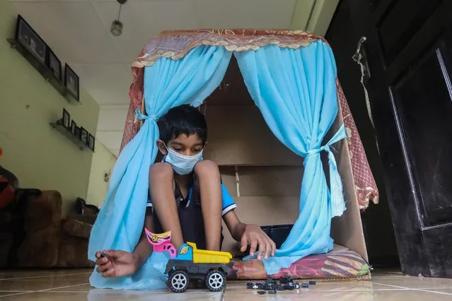 A Sri Lankan child plays inside a toy house during an island-wide lockdown as a preventive measure against the spread of the COVID-19, in Colombo, Sri Lanka, 01 October 2021. Sri Lanka celebrates World Children's Day on October 1. Events on this day attempt to raise public awareness on the rights of children. Children are the hardest hit during the ongoing pandemic with their educational activities being severely curtailed. Sri Lanka began administering the Covid-19 vaccines to children aged from 12 to 19 years who have comorbidities and are disabled from 24 September under doctors' observations. (Photo by Chamila Karunarathne/EPA/EFE)