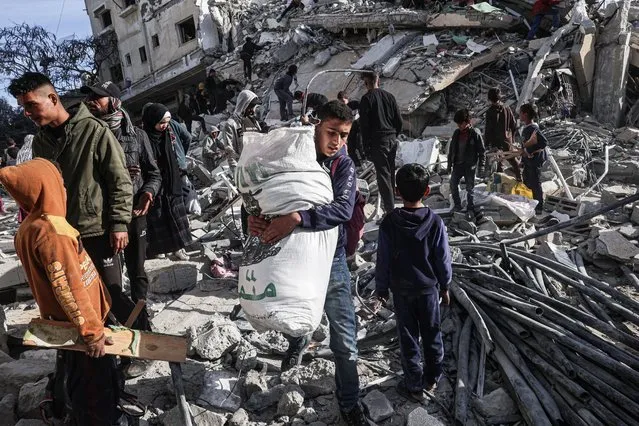 A Palestinian youth walks away with some items salvaged from the rubble of a residential building hit in an overnight Israeli air strike in Rafah in the southern Gaza Strip on March 9, 2023, amid continuing battles between Israel and the Palestinian militant group Hamas. (Photo by Said Khatib/AFP Photo)