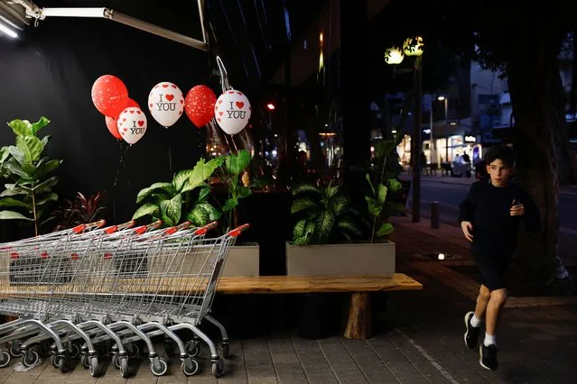 A boy runs past Valentine's Day decorations outside a supermarket, amid the ongoing conflict between Israel and the Palestinian Islamist group Hamas, on Valentine's Day in Tel Aviv, Israel on February 14, 2024. (Photo by Susana Vera/Reuters)