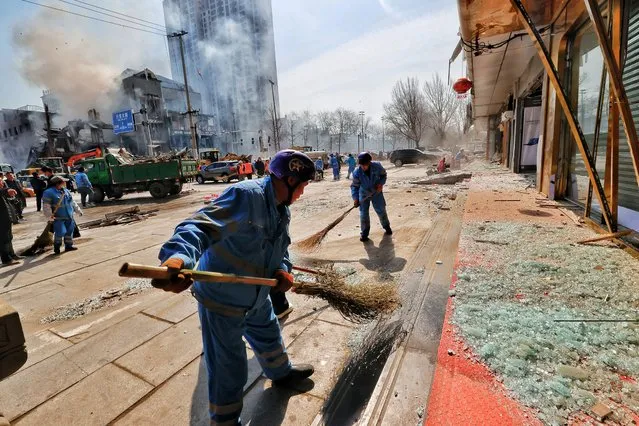 Workers clean up debris on the ground near the site of a restaurant explosion in Sanhe, Hebei province, China on March 13, 2024. (Photo by Reuters/China Daily)