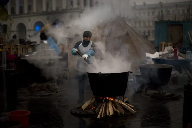 A woman cooks food for anti-Yanukovych protesters at Kiev's Independence Square, Ukraine, Monday, March 3, 2014. Russia pressed hard Monday for Ukrainian politicians to return to the February 21 agreement that promised to create a new unity government which would rule until an early election no later than December. (Photo by Emilio Morenatti/AP Photo)