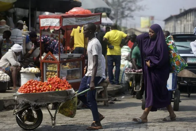 In this December 24, 2020, file photo, people walk in a market in Lagos, Nigeria. A survey of people aged 18-24 in 15 countries has found that many Africans are battling the economic downturns caused by the COVID-19 pandemic, losing jobs and seeing their education disrupted. Some of them turn to selling farm produce or other goods on the street. (Photo by Sunday Alamba/AP Photo/File)