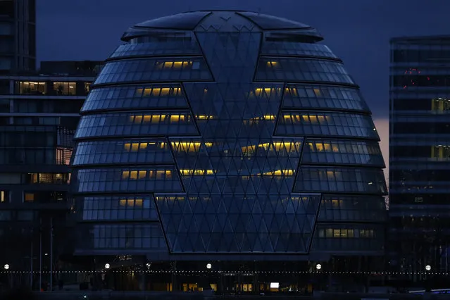 City Hall on the south bank of the Thames in London is illuminated in the evening of Saturday, March 6, 2021. (Photo by Alastair Grant/AP Photo)