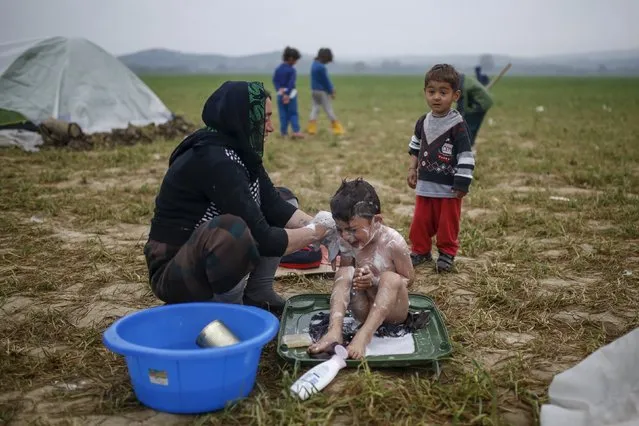 A woman bathes a child at a makeshift camp for migrants and refugees at the Greek-Macedonian border near the village of Idomeni, Greece, April 3, 2016. (Photo by Marko Djurica/Reuters)