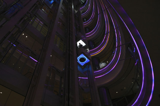 A man looks around as he rides a lift at a mall in a business district in Beijing on April 16, 2024. (Photo by Wang Zhao/AFP Photo)