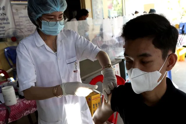 A Cambodian man, right, receives a shot of fourth dose of the Pfizer's COVID-19 vaccine at a heath center in Phnom Penh, Cambodia, Friday, January 14, 2022. Cambodia on Friday began a fourth round of vaccinations against the coronavirus, following the recent discovery of cases of the omicron variant, with high-risk groups being the first to receive them. (Photo by Heng Sinith/AP Photo)