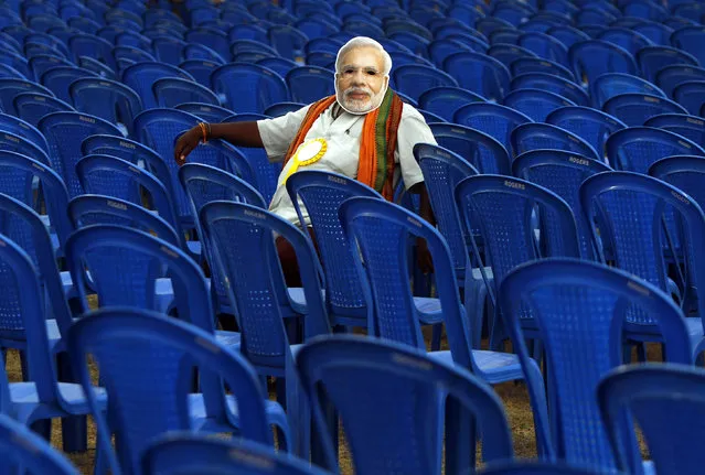 A supporter of Hindu nationalist Narendra Modi, prime ministerial candidate for India's main opposition Bharatiya Janata Party (BJP), wears a mask depicting Modi as he sits before the start of an election campaign rally in the southern Indian city of Chennai April 13, 2014. Modi on Saturday sought to blunt criticism that he is hostile to Muslims, the country's biggest minority group. (Photo by Reuters/Babu)