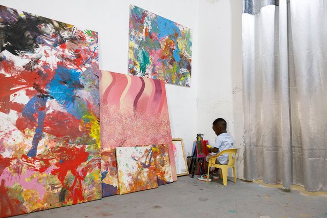Ace-Liam Nana Sam Ankrah, who will turn two in July, paints amidst his own art work at his mother's art gallery in Accra, Ghana, Monday, May 27, 2024. Ankrah has set the record as the world's youngest male artist. His mother, Chantelle Kukua Eghan, says it all started by accident when her son, who at the time was 6 months old, discovered her paints. (Photo by Misper Apawu/AP Photo)