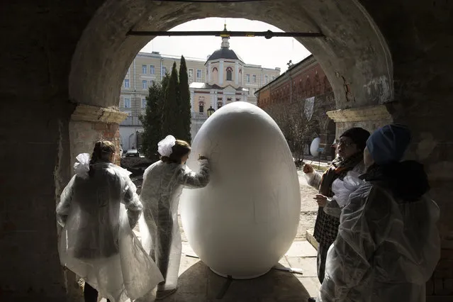 Children paint a huge symbolic egg in preparation for Orthodox Easter, after the Palm Sunday mass at the St. Peter's Cathedral in the High-Petrovsky monastery in Moscow, Russia, on Sunday, April, 9, 2017. (Photo by Alexander Zemlianichenko Jr./AP Photo)