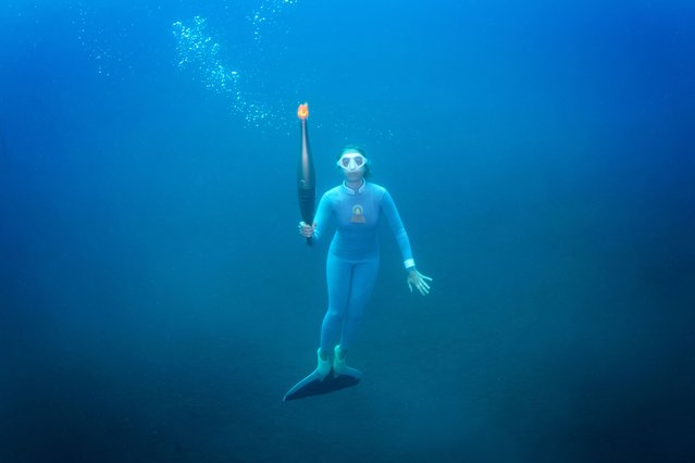 In this handout photograph taken and released by The Paris 2024 press service on June 18, 2024, French freediver champion Alice Modolo holds the Olympic torch underwater in the Mediterranean Sea as part of the Olympic torch relay in Villefranche-sur-mer, ahead of the Paris 2024 Olympic Games. (Photo by Samuel Jeglot/Poisson Lune Productions/Paris 2024/AFP Photo)