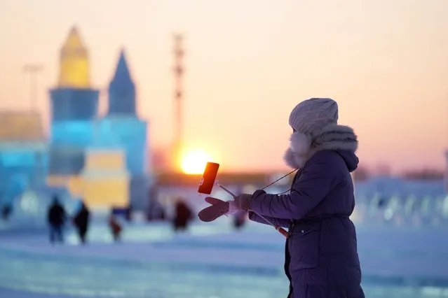 A tourist takes photos at the Harbin Ice-Snow World in Harbin, northeast China's Heilongjiang Province, December 25, 2021. The 23rd Harbin Ice-Snow World opened to the public on Saturday. (Photo by Wang Jianwei/Xinhua News Agency)