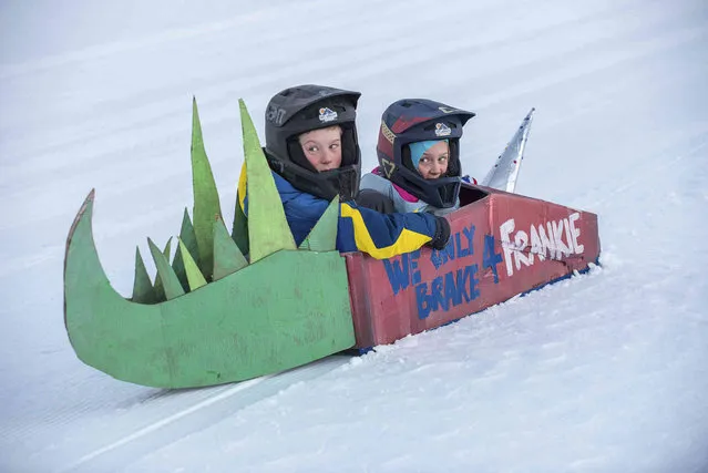 Charlie Luetje, left and his sister Ade look back up the hill after coming to a stop during a cardboard bobsled race on the hill behind Telstar High School, Friday, March 4, 2022, in Bethel, Maine. They built the sled last week with their father and grandfather during school vacation. The school district PTA sponsored the event where the only materials that could be used were cardboard, glue and duct tape. Prizes were awarded based on the fastest, farthest, most spirited, and epic fail. (Photo by Russ Dillingham/Sun Journal via AP Photo)