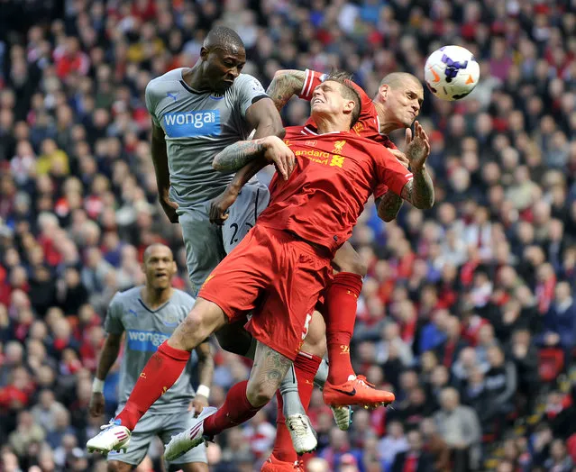 Liverpool's Daniel Agger, center, and Martin Skrtel, right, jump for the ball with Newcastle United's Shola Ameobi during their English Premier League soccer match at Anfield in Liverpool, England, Sunday May 11, 2014. (Photo by Clint Hughes/AP Photo)