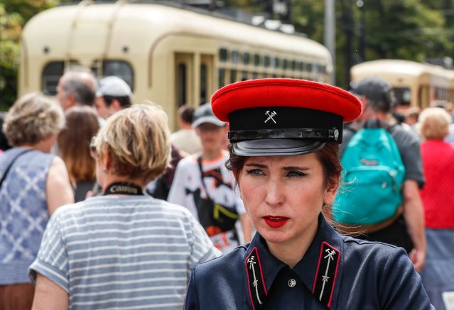 A woman wears a conductor's uniform as people look at various retro trams during the street exhibition “Retro Tram Parade” as part of marking the 125th anniversary of the city tramway service in Moscow, Russia on 13 July 2024. (Photo by Yuri Kochetkov/EPA/EFE)