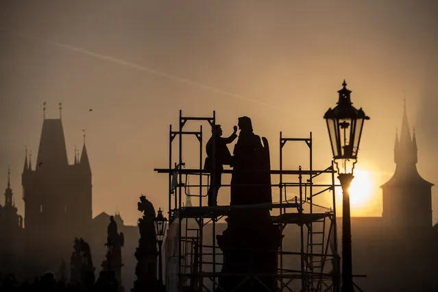 A restorer works on statue on Charles Bridge early in the foggy morning in Prague, Czech Republic, 25 October 2019. Meteorologists predict sunny weather with temperatures around 18 degrees Celsius in the next days in Czech Republic. (Photo by Martin Divisek/EPA/EFE)