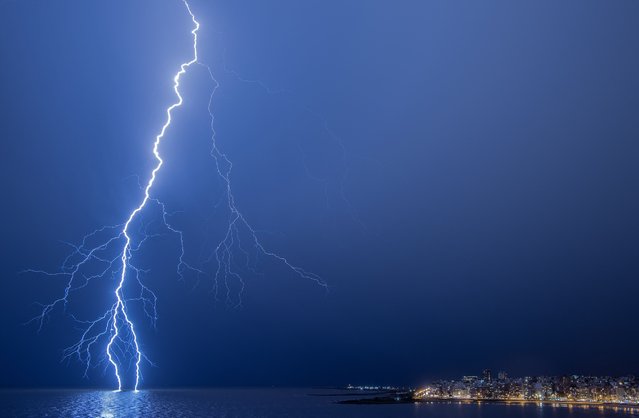 A lightning strikes during a thunderstorm in Montevideo on March 12, 2024. (Photo by Mariana Suarez/AFP Photo)