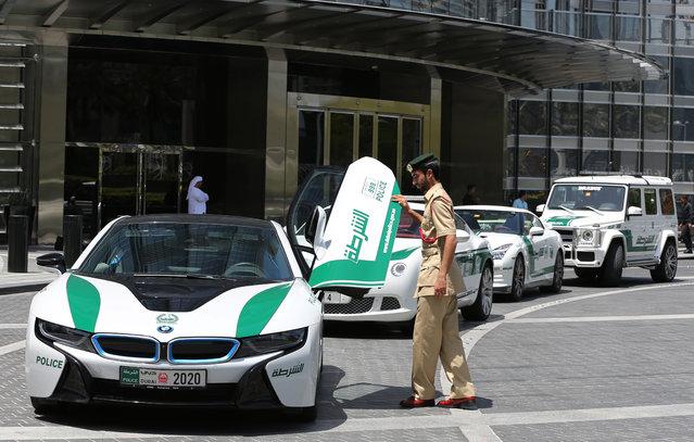 In this Thursday May 19, 2016 photo, Dubai police Lt. Saif Sultan Rashed al-Shamsi, who oversees the tourist police's patrol section, pushes down one of the twin scissor doors of the $140,000 BMW i8 during a demonstration in Dubai, United Arab Emirate. Police in Dubai have built up a high-horsepower arsenal of luxury sports cars and SUVs over the years to complement its fleet of green-and-white patrol cruisers. They say it is a way to reach out to the community and make their officers more accessible to the public in a country home to huge foreign workforce. (Photo by Kamran Jebreili/AP Photo)